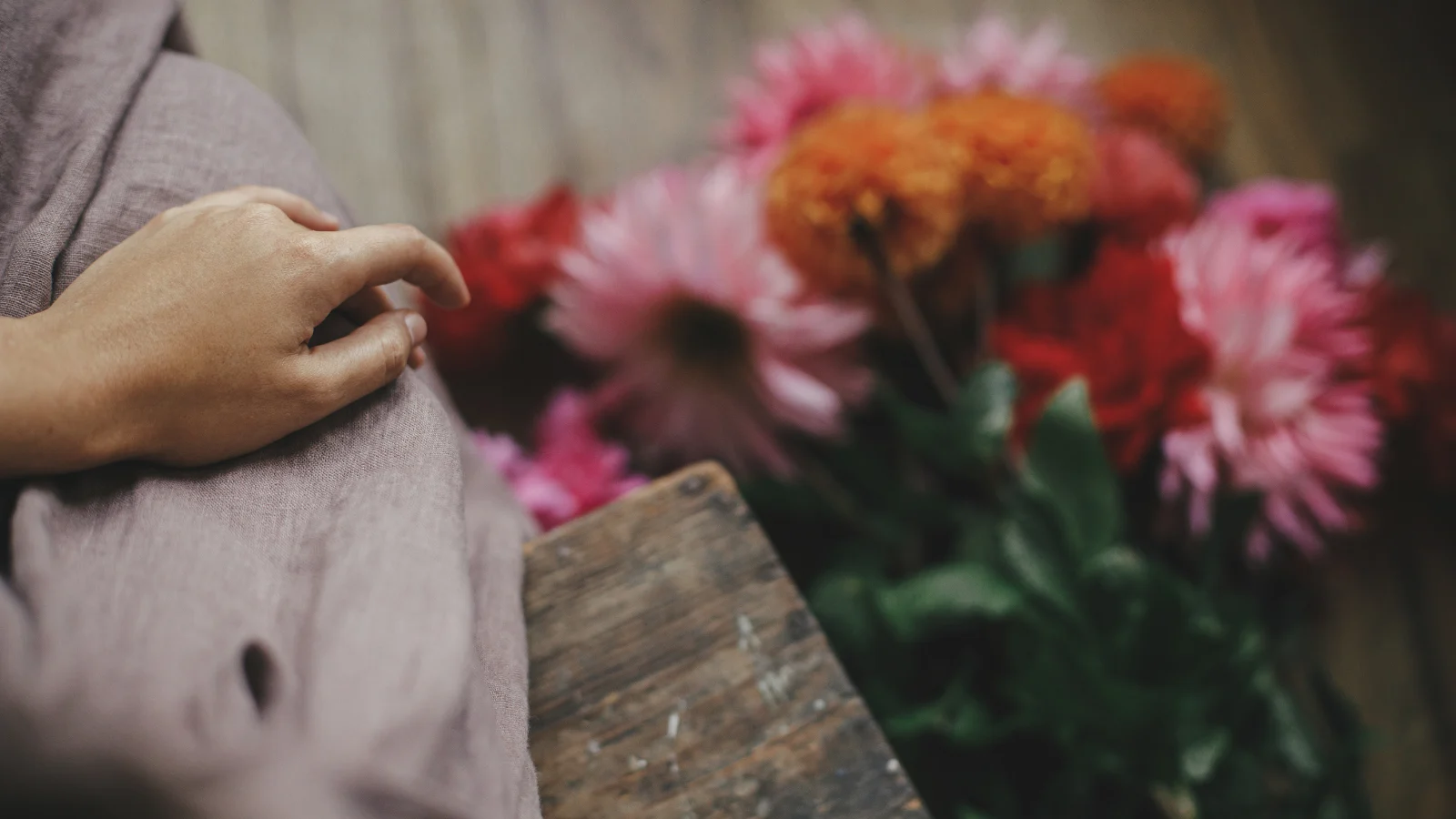 Person sitting beside flowers while grieving